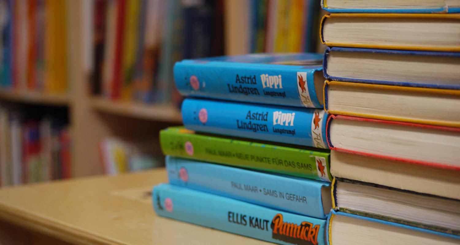 Bücher auf einem Stapel vor Bücherregal